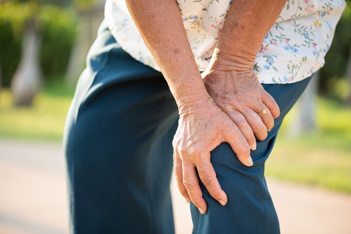Asian old woman walking in park and having knee pain, knee injury in park. Senior healthcare concept. degenerative knee pain
