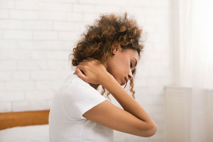 Woman suffering from neck pain, waking up in the morning, sitting on bed cervical radiculopathy